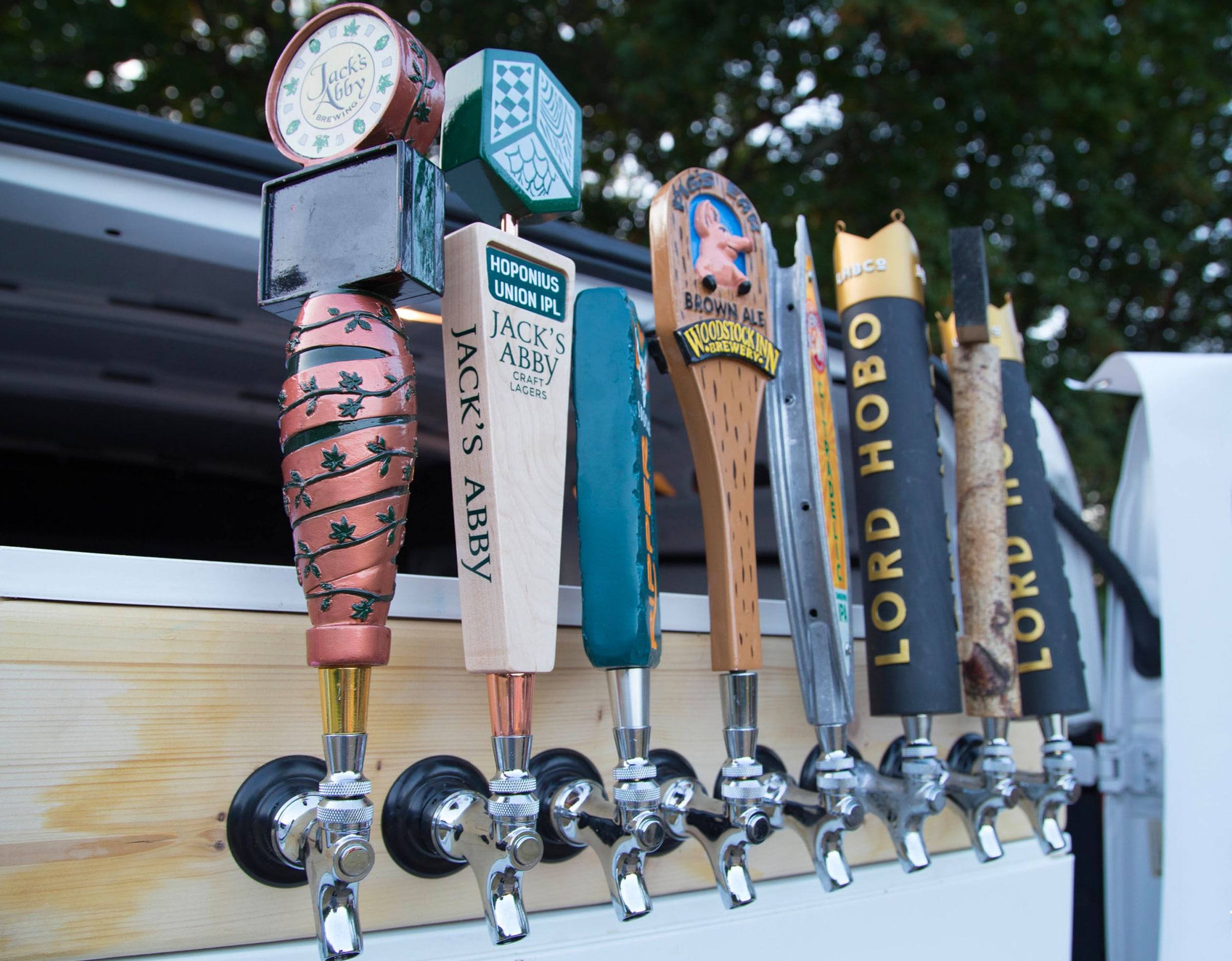 Craft beer tap handles lined up on the side of The Beer Mobile truck
